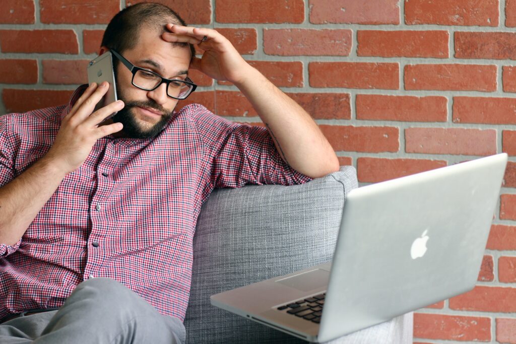 Profissional preocupado ao telefone em frente ao laptop, representando o medo da inteligência artificial no mercado de trabalho.