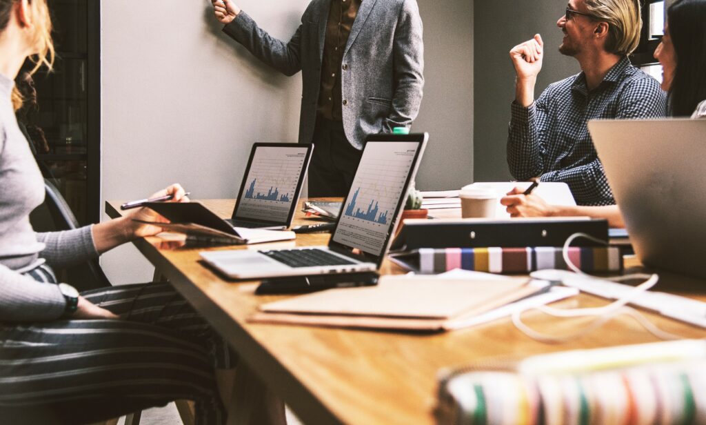 Profissionais em reunião analisando dados com laptops, representando inteligência artificial no mercado de trabalho.